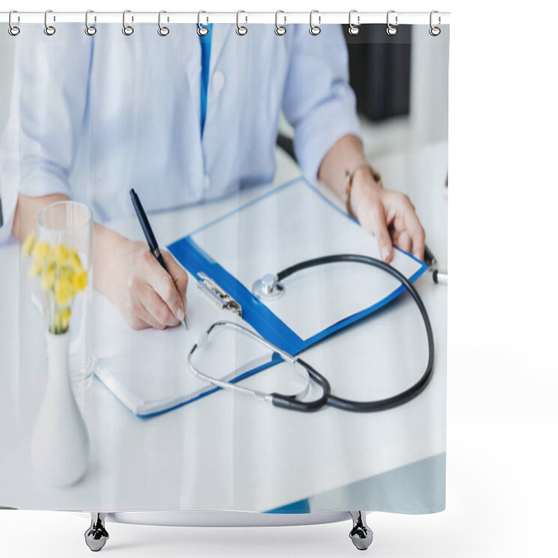 Personality  cropped image of female doctor writing in clipboard at table with stethoscope in office  shower curtains